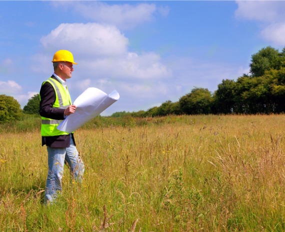 A civil engineer looking at their plans and a field, in the process of Site Planning in Nashville TN